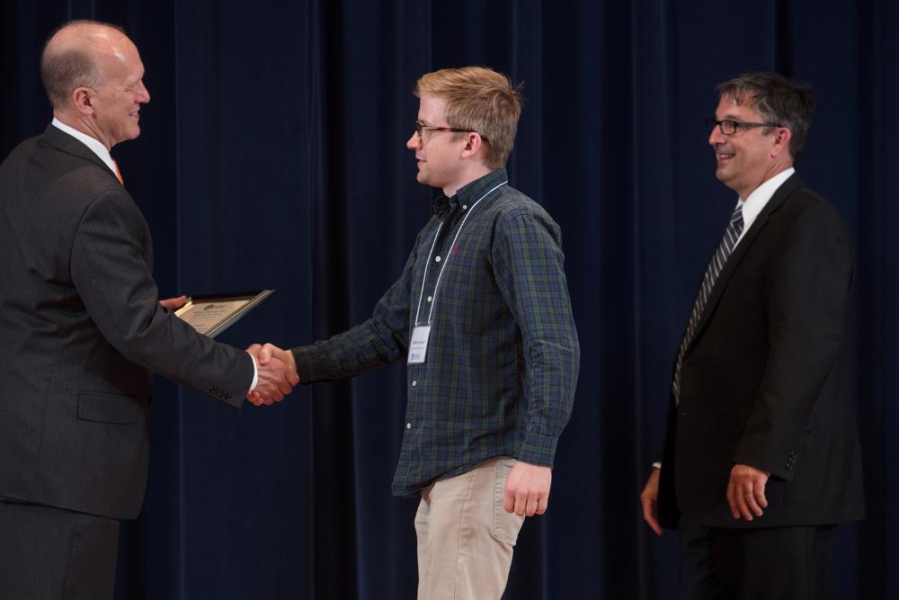 Doctor Potteiger shaking hands with an award recipient in a green flannel shirt